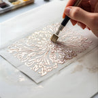 Hand painting intricate floral design with metallic paint using fine brush on paper