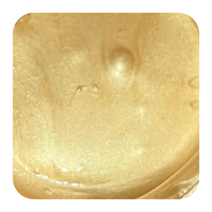 Shimmering gold cosmetic cream texture in a container, ideal for makeup or skincare routines.