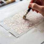 Hand painting intricate floral design with metallic paint on paper using fine brush